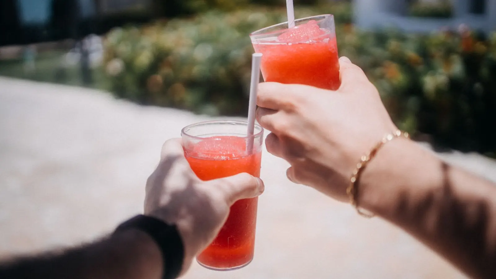 To hender som skåler med røde slush-drikker utendørs