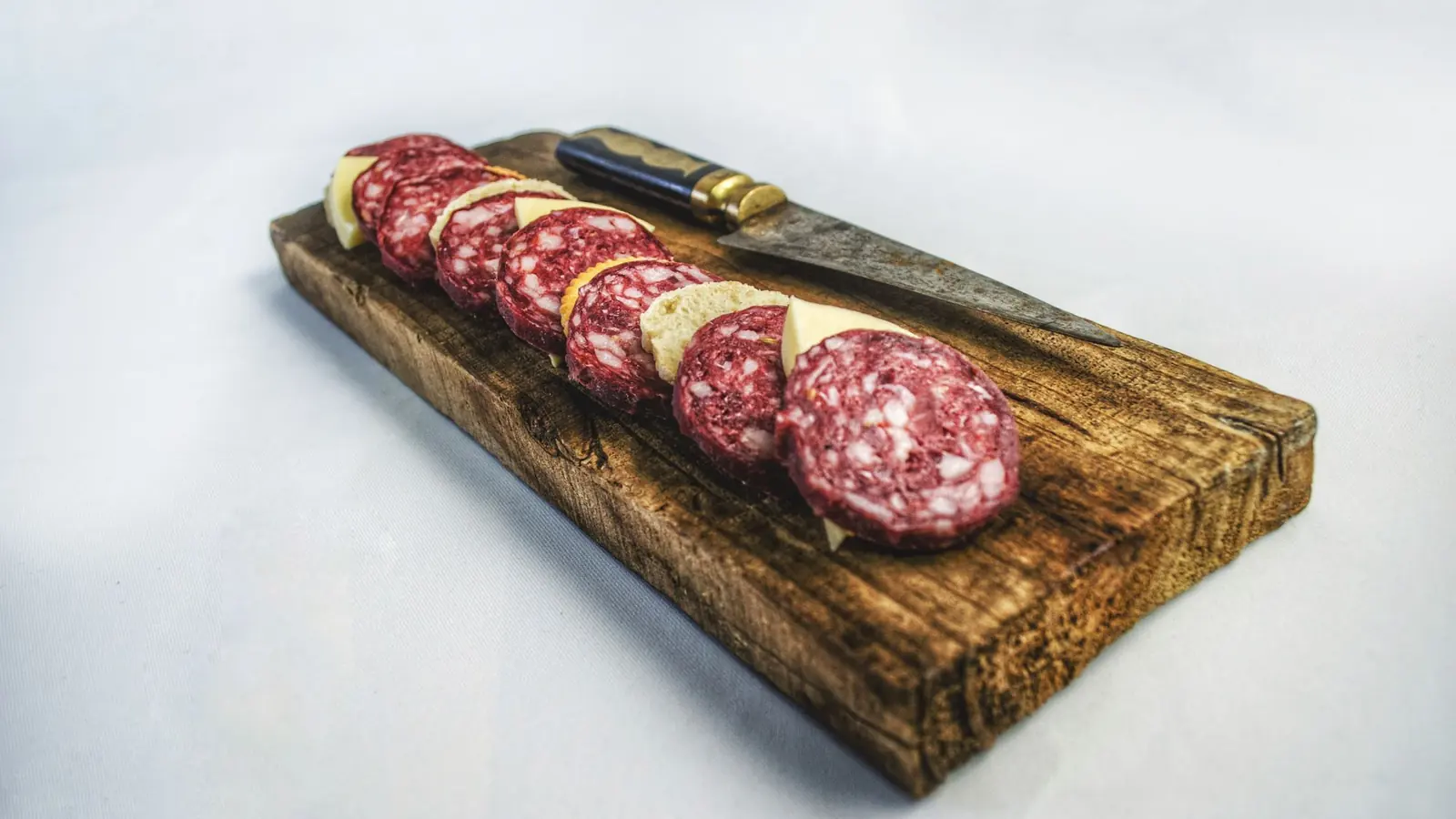 Skiver av spekepølse på et trebrett, med en kniv