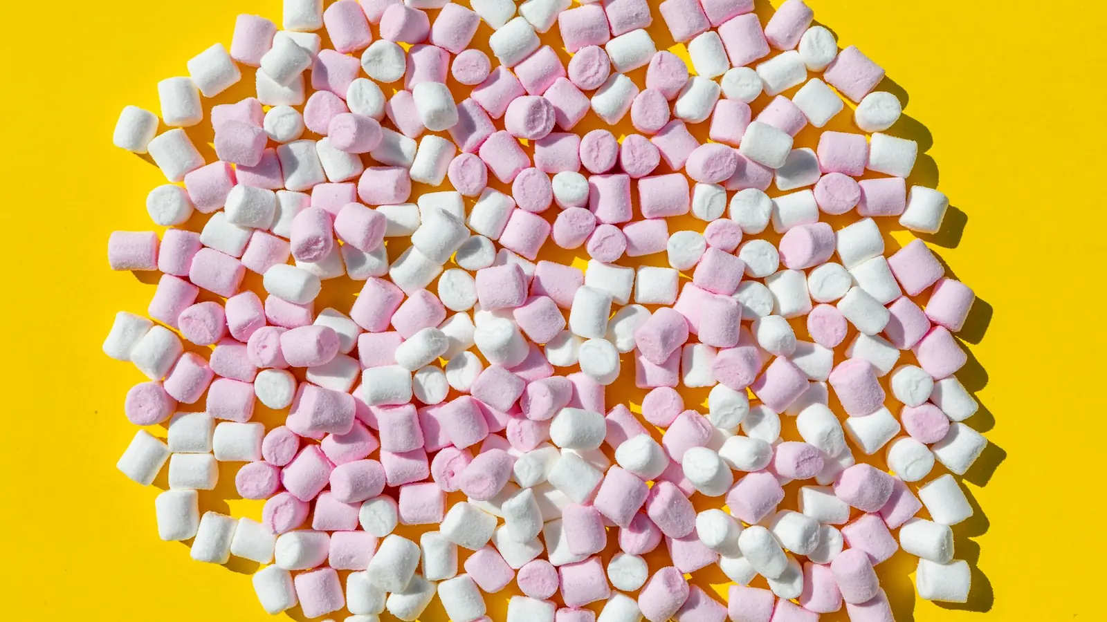 Hvite og rosa minimarshmallows på gul bakgrunn
